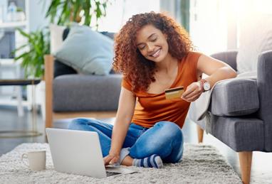 shot of a young woman using a laptop and credit card in the living room at home