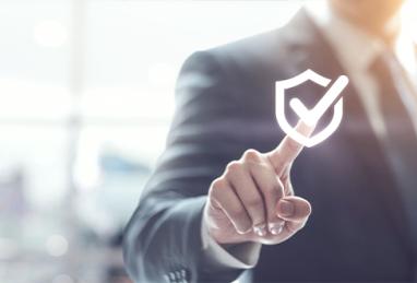 Businessman pressing security shield with check mark icon with blurred office background
