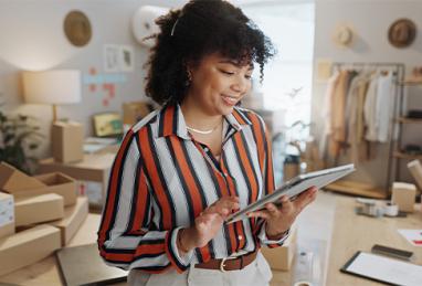 small business and happy woman with package logistics and order information for shipping working on her tablet